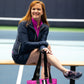 Woman siting on bench on court, with pink designer pickleball tote, navy and pink activewear