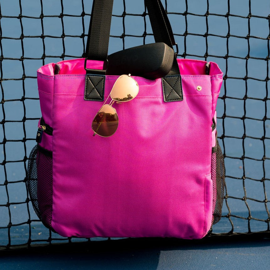 Pink Gasparilla Pickleball and Tennis Tote with Revo Relay Aviator sunglasses and protective case hanging from net