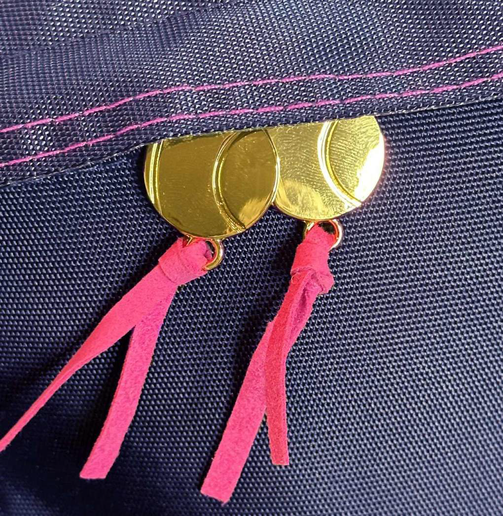 Goldtone tennis ball zipper pulls on sports backpack. With pink suede trim and accent stitching.