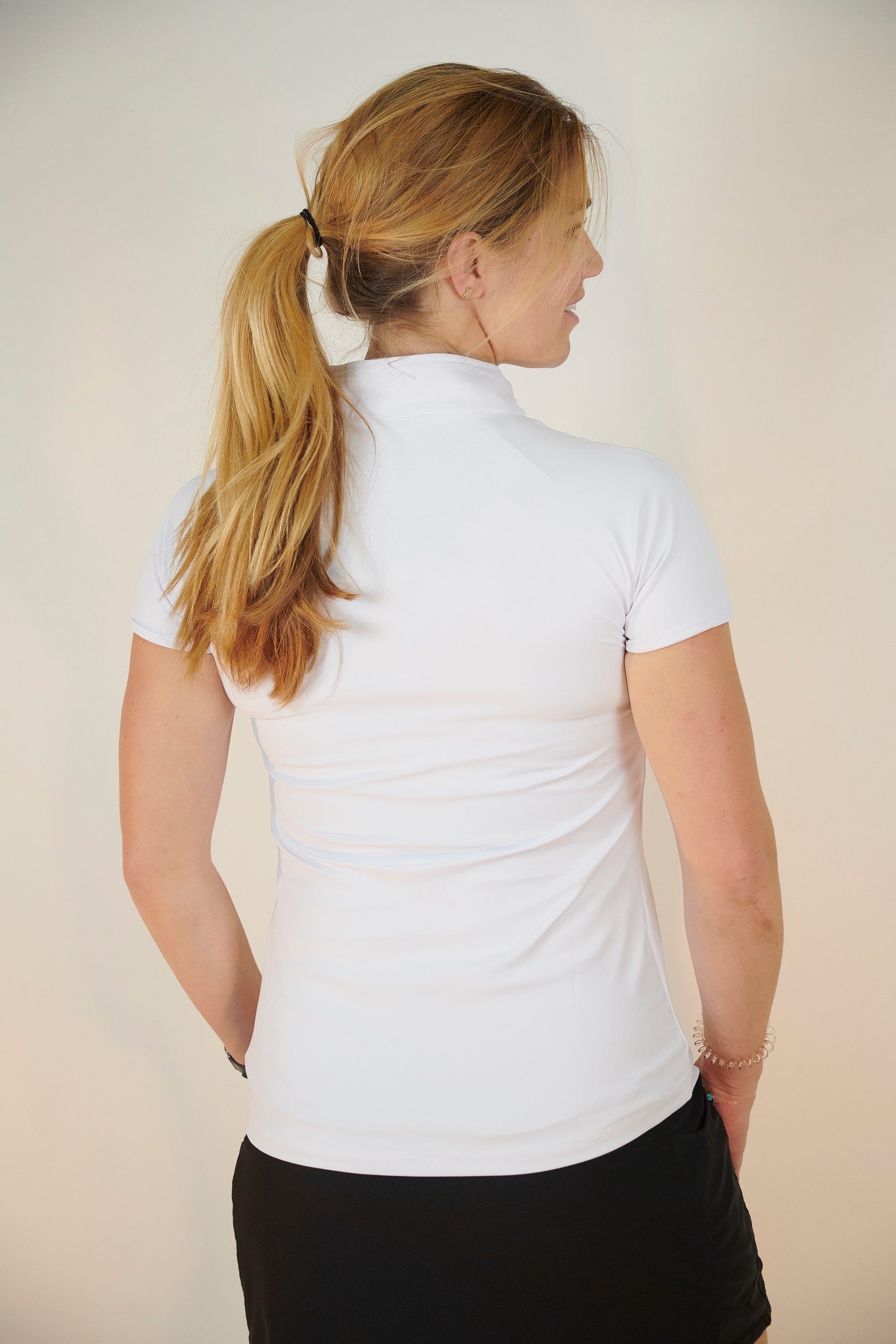 Back view of women in designer white shortsleeve Skea activewear top