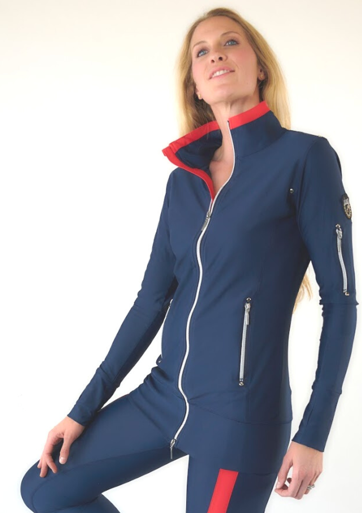 Woman wearing Sandy Navy full-zip jacket and matching navy leggings with red stripe