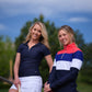Two women in Skea activewear on golf course with trees and sky in background