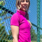 Woman in front of tennis fence wearing Skea designer activewear top in Orchid 
