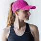 Woman wearing pink baseball cap by VIMHUE, front view with ponytail through hole in top of cap