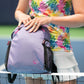 zoomed view of woman wearing rainbow leaves top and white skort holding designer pickleball backpack
